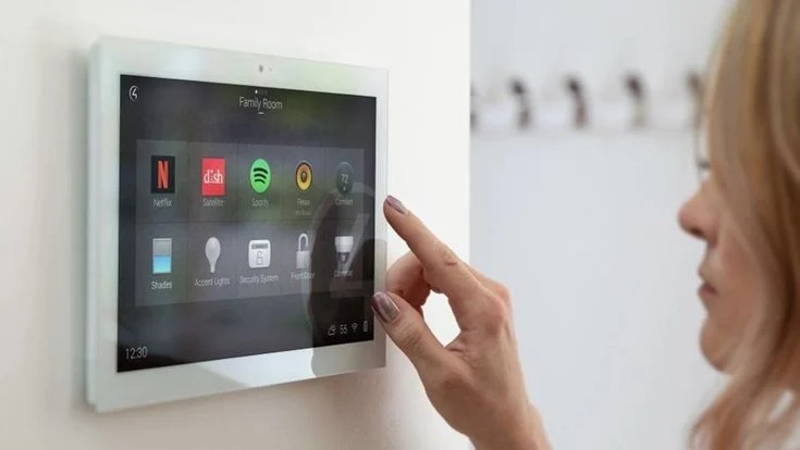 Persona utilizando una pantalla de control domótico Control4 en una pared